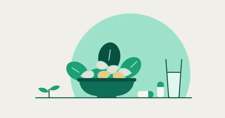 A bowl of leafy greens and almonds beside two capsules, one lying and one standing, a glass of water and a small sprout